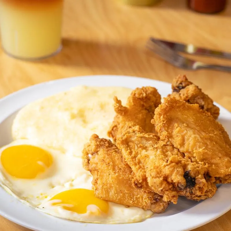 Fried chicken wings served with two fried eggs